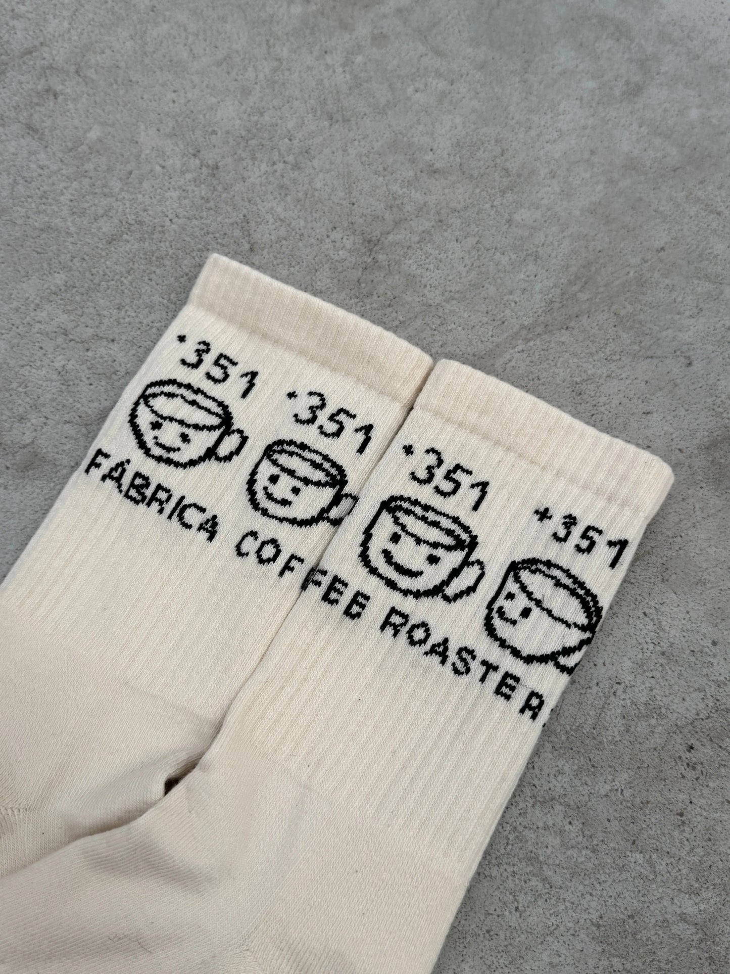 Pair of white socks with black text and smiley face designs on a gray surface