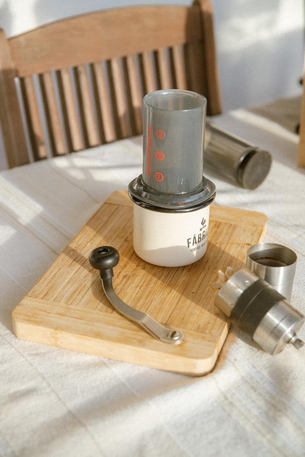 Coffee brewing apparatus on a wooden cutting board with a white cloth background