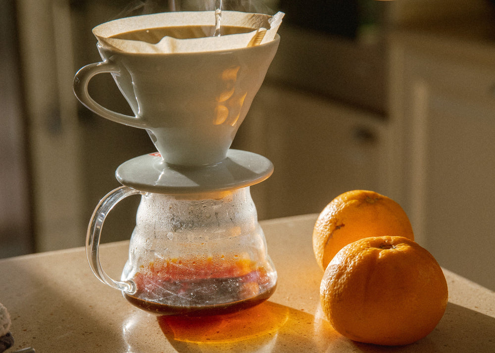 pour over coffee being served with oranges and beautiful sunlight