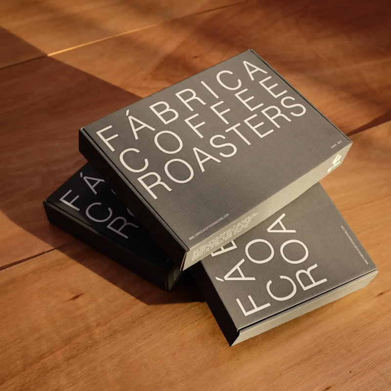 Two boxes from Fabrica Coffee Roasters on a wooden surface