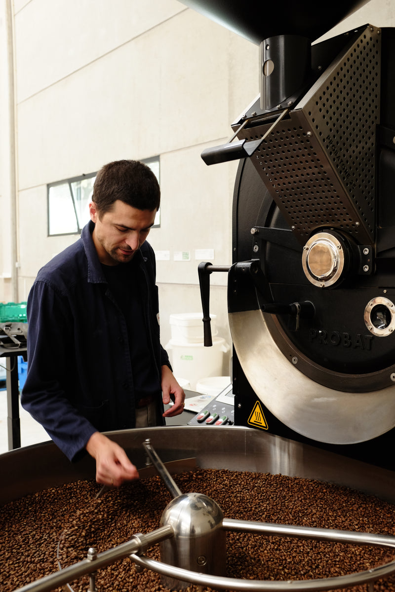 Person operating a coffee roasting machine in a coffee shop.
